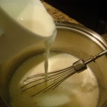Пресейте брашното, разбъркайте с ванилията и захарта. Загрейте млякото и сложете жълтъците в него. Изсипете сместа с брашното и захарта, разбъркайте. Пригответе сместа на слаб огън до кипване, разбърквайте непрекъснато за около 15 минути, за да се сгъсти и не стане на бучки. Премахнете от котлона и оставете да се охлади. Добавете останалото масло и коняк, разбъркайте за 2-3 минути.