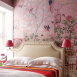 Интериор спалня с бяло легло, розови лампи и фототапет разцъфнало дърво