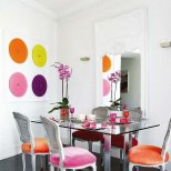 Интериор за трапезария с маса стъкло и разноцветни столове
