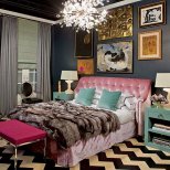 Интериор за спалня с лилаво легло, сиви стени, табуретка циклама и килим бяло и черно