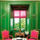 Интериор с неокласически стил с ярко зелени стени, розови столове и малка светла масичка за чай