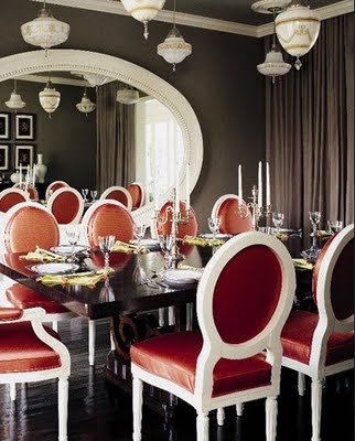 Интериор за трапезария с черна голяма правоъгълна маса и червени столове с бели рамки